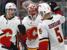 Calgary Flames goaltender Mike Smith, center, is congratulated by teammates Mark Giordano (5) and Travis Hamonic (24) after a 4-3 victory against the San Jose Sharks in a preseason NHL hockey game in San Jose, Calif., Thursday, Sept. 27, 2018.