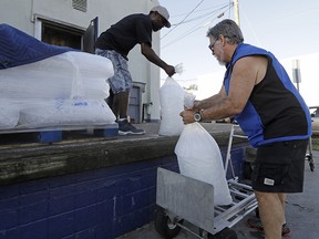 Stan Atamanchuk, right, buys large bags of ice from Roase Ice & Coal days after Hurricane Florence in Wilmington, N.C. Many in Wilmington woke up Wednesday exhausted. The days-long scavenger hunt for gas and ice was over as stores opened and relief agencies were able to roll into the city.
