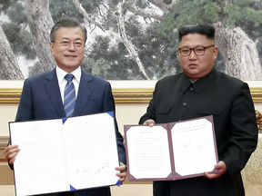 In this image made from video, South Korean President Moon Jae-in, left, and North Korean leader Kim Jong-Un pose after signing documents in Pyongyang, North Korea, Sept. 19, 2018.