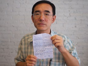 Sun Yi holding the SOS letter he wrote, that made its way around the world and back to him. From the film Letter From Masanjia, at Calgary International Film Festival.