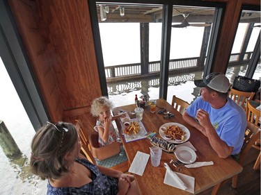 Blythe Hayes, left, with her daughter Erin Hayes, 3, and her husband Sean Hayes, from Manteo, N.C., eats at Bubba's Seafood Restaurant even though the deck has a few inches of water on it, Friday, Sept. 14, 2018, in Virginia Beach, Va., as the effects of Hurricane Florence are felt in the area.