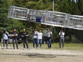 FILE - In this Saturday, June 3, 2017, file photo, Tsubasa Nakamura, project leader of Cartivator, third from left, watches the flight of the test model of the flying car on a former school ground in Toyota, central Japan. The Japanese government has started a "flying car" project, bringing together more than a dozen companies, including All Nippon Airways, electronics company NEC, Toyota-backed startup Cartivator and Uber, the ride-hailing service. Toyota and its group companies have also invested 42.5 million yen ($375,000) in a Japanese startup, Cartivator, that is working on a flying car.