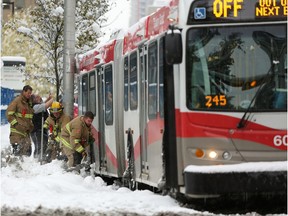 Firefighters help get a stuck bus moving at the intersection of 4th Street and 12th Avenue S.W. during an autumn snowstorm in Calgary on Tuesday. Oct. 2, 2018.