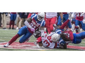 Calgary Stampeders running back Terry Williams (38) is taken to the ground by Montreal Alouettes linebacker Chris Ackie (21) and defensive back Dominique Ellis (3) during 2nd half CFL action at Molson Stadium in Montreal, on Monday, Oct. 8, 2018. Photo by Dave Sidaway/Postmedia.