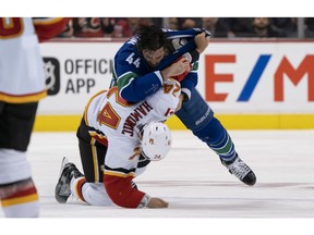 VANCOUVER, BC - OCTOBER 3: Erik Gudbranson #44 of the Vancouver Canucks knocks down Travis Hamonic #24 of the Calgary Flames during a fight in NHL action on October, 3, 2018 at Rogers Arena in Vancouver, British Columbia, Canada.