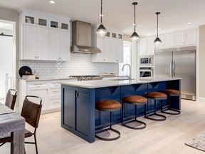 Glossy white subway tiles on the kitchen's backsplash serves to highlight the punch of blue provided by the island in the Cyprus II show home by Broadview Homes in Harmony.