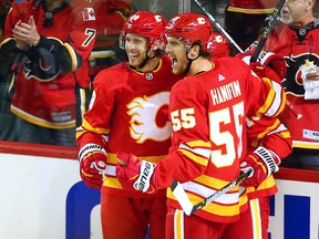 The Calgary Flames Elias Lindholm and Noah Hanifin celebrate with Johnny Gaudreau after his career 100th goal during NHL action against the Boston Bruins at the Scotiabank Saddledome in Calgary on Wednesday October 17, 2018.