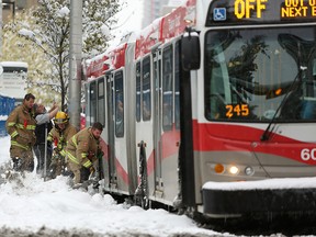 Firefighters help dig out a stranded bus at the intersection of 4th Street and 12th Avenue S.W. during a snowstorm in Calgary on Tuesday Oct. 2, 2018.