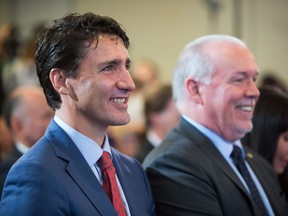 Prime Minister Justin Trudeau, left, and B.C. Premier John Horgan smile while sitting together during an LNG Canada news conference in Vancouver on Tuesday, Oct. 2, 2018.