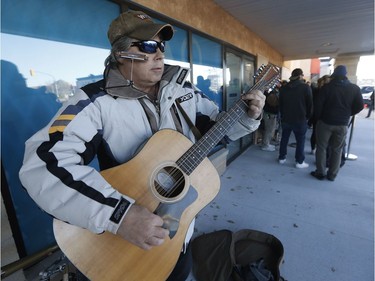 Don Poitras, plays guitar for the hundreds of people who line up outside a cannabis store to buy their first legal gram of marijuana in Winnipeg, Man., on Wednesday, October 17, 2018. Marijuana is now legal in Canada.