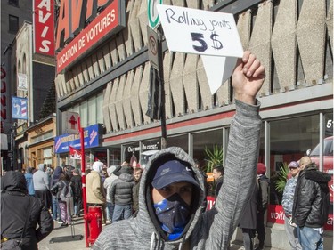 A man holds up a sign offering to roll marijuana joints for $5 at the lineup outside a government cannabis store, Wednesday, October 17, 2018 in Montreal as the legal sale of cannabis begins in Canada.