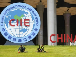In this Oct. 26, 2018, photo, workers trim the lawn in front of the National Exhibition and Convention Center, the venue for the upcoming China International Import Expo (CIIE) in Shanghai, China.