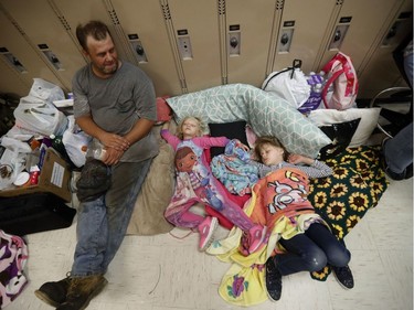 CORRECTS HURRICANE NAME TO MICHAEL NOT MATTHEW - Earnest Sweet sits while his daughters Terri, 4, center, and Anna, 7, sleep at an evacuation shelter set up at Rutherford High School, in advance of Hurricane Michael, which is expected to make landfall today, in Panama City Beach, Fla., Wednesday, Oct. 10, 2018.
