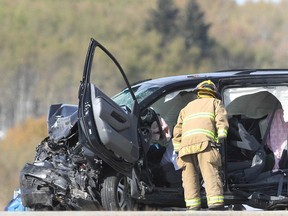 A firefirefighter attends the scene a two-vehicle crash on Hwy 22 near Township Road 274, north of Cochrane on Friday, Oct. 5, 2018. A woman died in the crash.