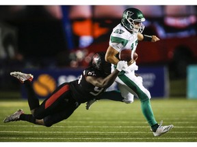 Saskatchewan Roughriders quarterback Zach Collaros, right, tires to escape from Calgary Stampeders' Ja'Gared Davis, during CFL football action in Calgary, Saturday, Oct. 20, 2018.