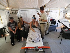 Aleeah Racette receives medical treatment inside the Florida 5 Disaster Medical Assistance Team tent, outside the Bay Medical Sacred Heart hospital, in the aftermath of Hurricane Michael in Mexico Beach, Fla., Thursday, Oct. 18, 2018. At left is her mother, Amy Cross, and Amy's fiance, Corey Shuman.