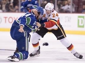 Erik Gudbranson of the Vancouver Canucks tangles with Flames defenceman Travis Hamonic on Oct. 3, 2018 at Rogers Arena in Vancouver.