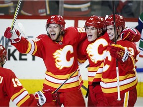 The Calgary Flames' Elias Lindholm, left, of Sweden, celebrates his second goal with teammate Matthew Tkachuk, centre, and Sean Monahan during NHL hockey action against the Vancouver Canucks, in Calgary on Saturday, Oct. 6, 2018.