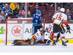 Calgary Flames goalie Tyler Parsons (82) makes a save as Vancouver Canucks' Olli Juolevi (48), of Finland, falls on top of him during the third period of a pre-season NHL hockey game in Vancouver, B.C., on Wednesday September 19, 2018.
