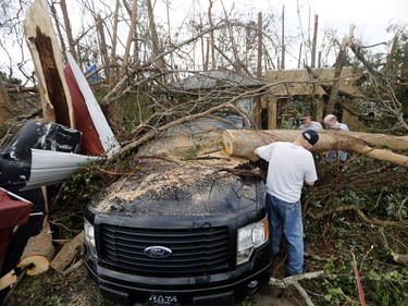 People cut away a tree that'll on a vehicle in the aftermath of Hurricane Michael in Panama City, Fla., Thursday, Oct. 11, 2018. (AP Photo/Gerald Herbert) ORG XMIT: FLGH102