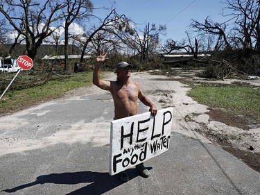 Michael Williams, 70, waves to passing motorists while looking for food and water as downed trees prevent him from driving out of his damaged home with his family in the aftermath of Hurricane Michael in Springfield, Fla., Thursday, Oct. 11, 2018. "I don't know what I'm going to," said Williams. (AP Photo/David Goldman) ORG XMIT: FLDG105
