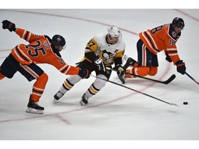 Pittsburgh Penguins Sidney Crosby (87) splits the Edmonton Oilers defence Darnell Nurse (25) and Ryan Strome (18) to score in overtime during NHL action at Rogers Place in Edmonton on Tuesday night. Photo by Ed Kaiser/Postmedia.