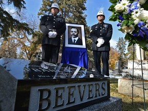 Sgt. Cliff Reimer, left, and retired Sgt. Darren Zimmerman, dressed in period clothing, stand next to a photo of Const. Frank Beevers, the first Edmonton police officer killed in the line of duty who was honoured with a monument dedication at the Edmonton Cemetery on Thursday, Oct. 11, 2018 after it was discovered his grave was left unmarked for nearly a century.