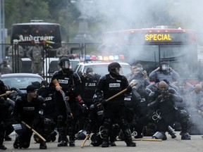 Police react to tear gas blown back in their faces after they tried to disperse a crowd of students gathered in the Oakland section September 24, 2009 in Pittsburgh, Pennsylvania. Police are responding to reports of an active shooting at a Pittsburgh synagogue.