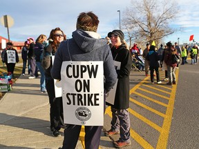 Striking postal workers walk a picket line at the northeast Calgary sorting centre on Thursday, Oct. 24, 2018. The workers began a 24-hour rotating strike at 6 p.m. on Wednesday.