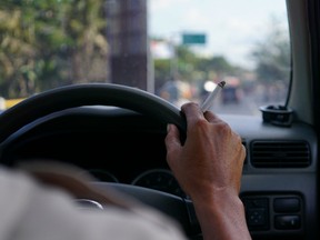 A person smokes while driving. Using pot before driving increases the risk of a crash even five hours after inhaling, new Canadian research finds.