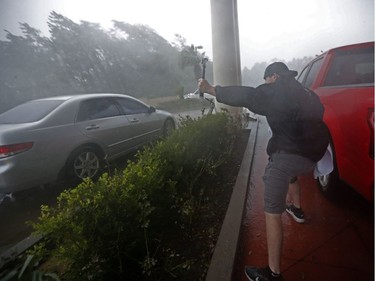A storm chaser films from underneath a hotel canopy during Hurricane Michael in Panama City Beach, Fla., Wednesday, Oct. 10, 2018.