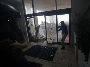 A hotel employee holds a glass door closed as it breaks from flying debris during Hurricane Michael in Panama City Beach, Fla., Wednesday, Oct. 10, 2018.