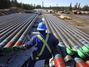 An oilfield worker moves production pipe at an oil pad at the Devon Jackfish facility site, in Conklin, Canada.
