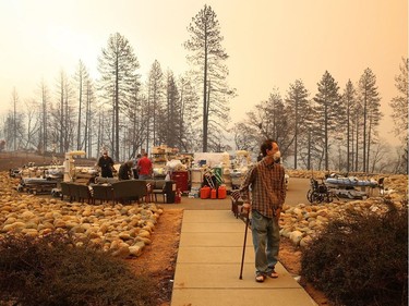 A patient walks away from a makeshift triage area as the the Feather River Hospital is evacuated during the Camp on November 8, 2018 in Paradise, California. Fueled by high winds and low humidity, the rapidly spreading Camp Fire has ripped through the town of Paradise and has quickly charred 18,000 acres and has destroyed dozens of homes in a matter of hours. The fire is currently at zero containment.