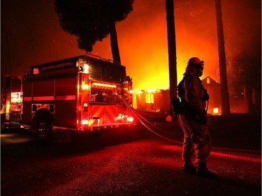 Firefighters try to save a building as the Camp Fire moves through the area on Nov. 8, 2018 in Paradise, California. Fuelled by high winds and low humidity, the rapidly spreading wildfire has ripped through the town of Paradise, charring 18,000 acres and destroying dozens of homes in a matter of hours. The fire is currently at zero containment.