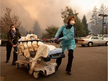 Patients are quickly evacuated from the Feather River Hospital as it burns down during the Camp fire in Paradise, California on November 08, 2018. - More than 18,000 acres have been scorched in a matter of hours burning with it a hospital, a gas station and dozens of homes.