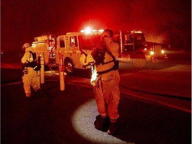 Firefighter Adrien Mahnke pauses while battling the Camp Fire as it tears through Paradise, Calif., on Thursday, Nov. 8, 2018. Tens of thousands of people fled a fast-moving wildfire Thursday in Northern California, some clutching babies and pets as they abandoned vehicles and struck out on foot ahead of the flames that forced the evacuation of an entire town and destroyed hundreds of structures.