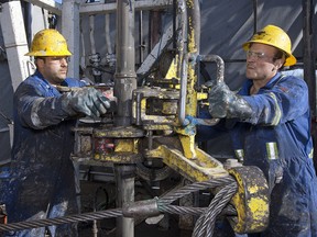 Floorhands John Emarel, left, and Charles Scott, work at Baytex Energy Ltd.'s Pembina oil field near Pigeon Lake, Alta., on Feb. 17, 2012.