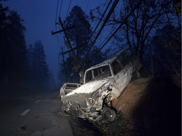 A scorched vehicle rests on a roadside as the Camp Fire tears through Paradise, Calif., on Thursday, Nov. 8, 2018. Tens of thousands of people fled a fast-moving wildfire Thursday in Northern California, some clutching babies and pets as they abandoned vehicles and struck out on foot ahead of the flames that forced the evacuation of an entire town and destroyed hundreds of structures.