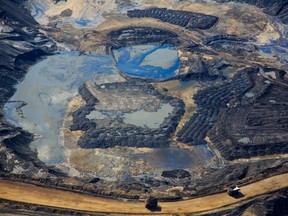 Aerial view of Canadian Natural Resources Ltd. oilsands mining operation near Fort McKay, Alta. Canada’s biggest producer is cutting production as prices plummet.