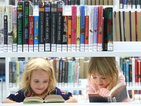 Sisters Sophie, 6 yrs, and Olivia, 4 yrs, dive into some books during the opening of the new library in Calgary on Thursday, November 1, 2018.