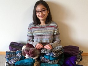 Allysa Narang, 13, with a pile of hats she knit and donated to the Calgary Drop-In Centre.