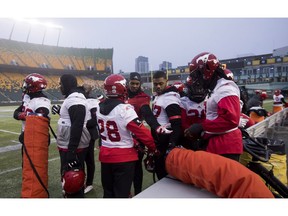 Members of the Calgary Stampeders huddle around a heater in Edmonton, Friday, November 23, 2018. The Ottawa Redblacks will play the Calgary Stampeders in the 106th Grey Cup on Sunday.