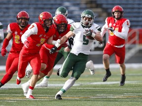 University of Saskatchewan Huskies' Tyler Chow is chased by the University of Calgary Dinos' defense during first half Hardy Cup CWUAA championship football action in Calgary, Saturday, Nov. 10, 2018.