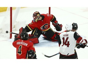 Calgary Flames goaltender Mike Smith, top, makes a save on a shot by Arizona Coyotes right wing Richard Panik (14) as Flames defenseman Rasmus Andersson (4) and defenseman Oliver Kylington (58) covered on the play during the second period of an NHL hockey game Sunday, Nov. 25, 2018, in Glendale, Ariz.