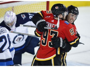 Calgary Flames' Sam Bennett, centre, celebrates his goal with teammate Matthew Tkachuk, right, as Winnipeg Jets goalie Connor Hellebuyck picks himself up during first period NHL hockey action in Calgary, Wednesday, Nov. 21, 2018.THE CANADIAN PRESS/Jeff McIntosh ORG XMIT: JMC106