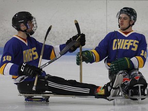 Humboldt Broncos hockey player Jacob Wassermann, left, and teammate Ryan Straschnitzki compare sticks during a sled hockey scrimmage at the Edge Ice Arena in Littleton, Colo., on Friday, Nov. 23, 2018. Both players were paralyzed from the waist down in the team's bus crash in April. THE CANADIAN PRESS/Joe Mahoney ORG XMIT: COJM103