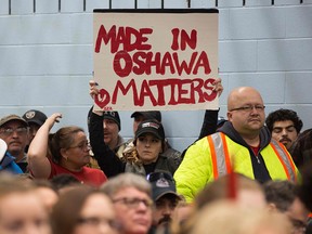 A woman holds a sign during the press conference with union leaders at Local 222 in Oshawa, Ont., on Nov. 26, 2018. In a massive restructuring, U.S. auto giant General Motors announced it will cut 15 per cent of its workforce.