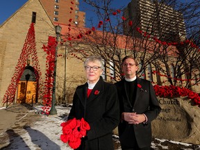 Pippa FitzGerald-Finch, left and Rev. Leighton Lee, Dean and Rector of the Cathedral Church of the Redeemer pose with some of the handmade poppies that adorn the Calgary church.