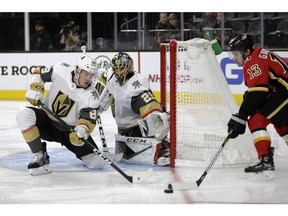 Vegas Golden Knights defenseman Nate Schmidt (88) and goaltender Marc-Andre Fleury (29) defend the shot against Calgary Flames left wing Johnny Gaudreau (13) during the third period of an NHL hockey game Friday, Nov. 23, 2018 in Las Vegas.